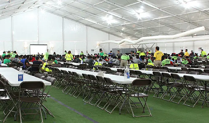 Structure tent set up with long tables for worker lunch