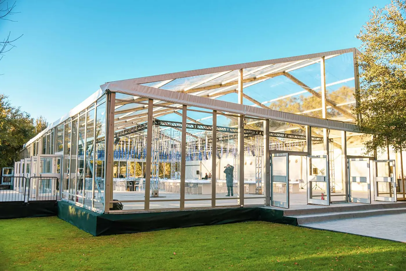 Image of the outside of a clear tent, looking inside to the decorations for an event 