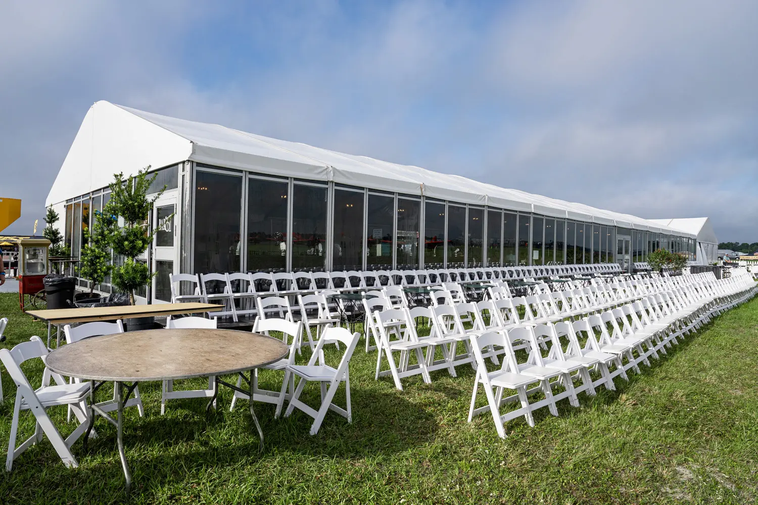 Rows of white chairs placed in front of a tent with clear walls
