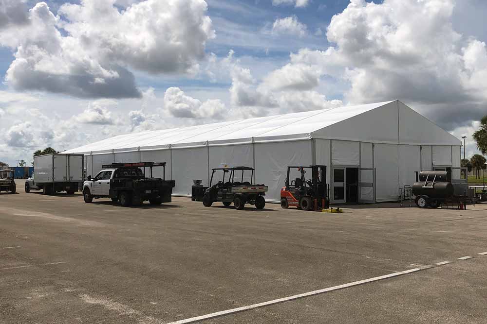 White tent with trucks and utility vehicles in the front
