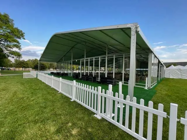 Short white fence in front of a large tent with clear walls