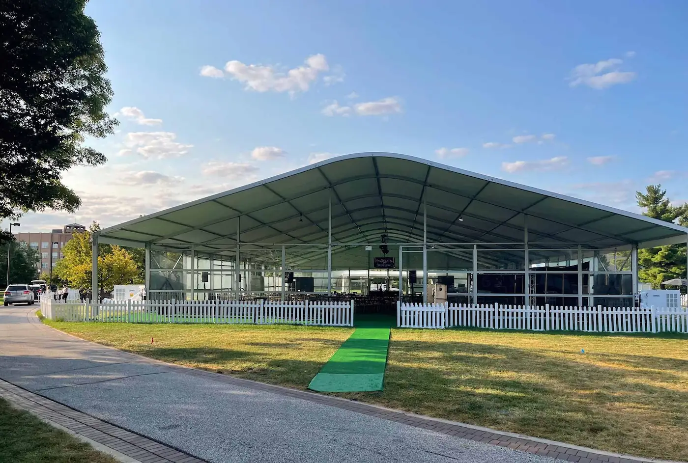 Green carpet on grass leading to a tent 