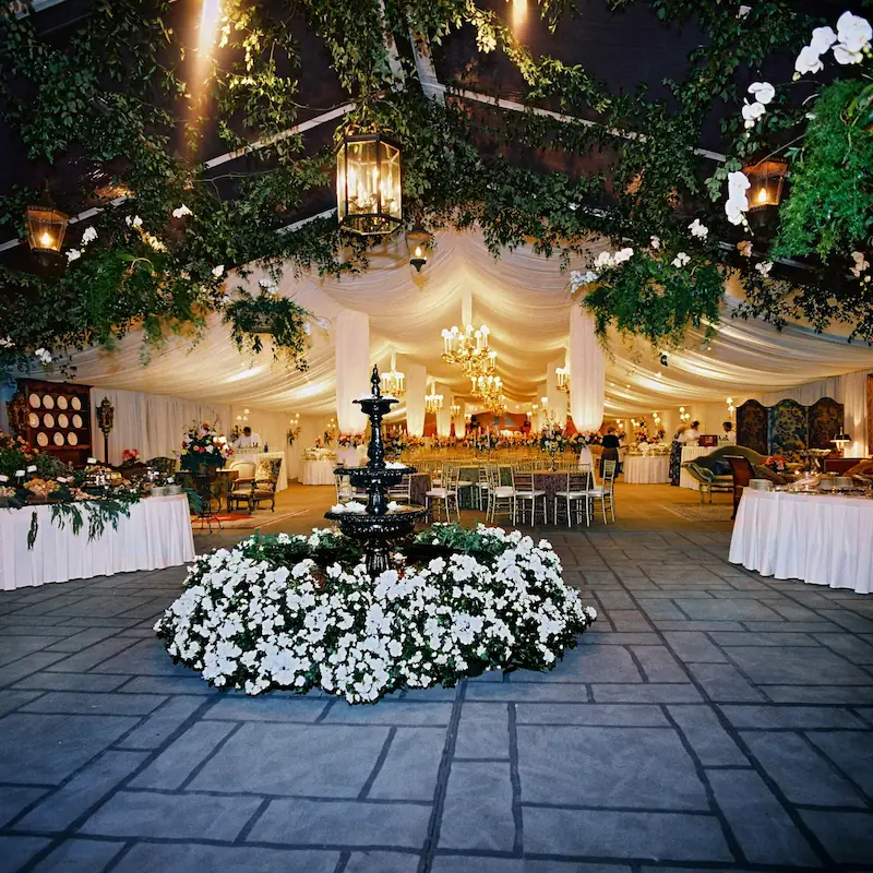 Large wedding tent ornately decorated with foliage, flowers and chandeliers.