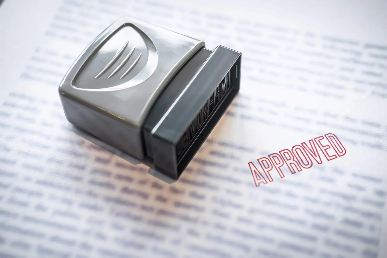 Image of a stamp and the words "approved" stamped on a paper