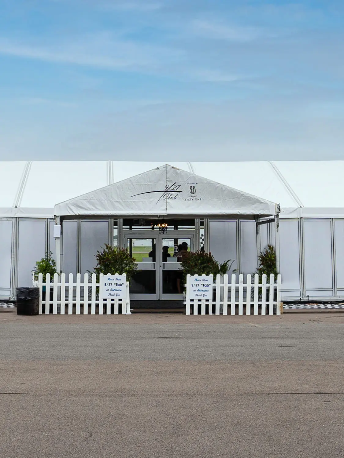 Side of large tent with double door entrance, decorations and fence upon entryway