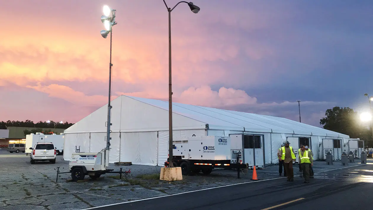 tent set up in parking lot with power generator powering large lights