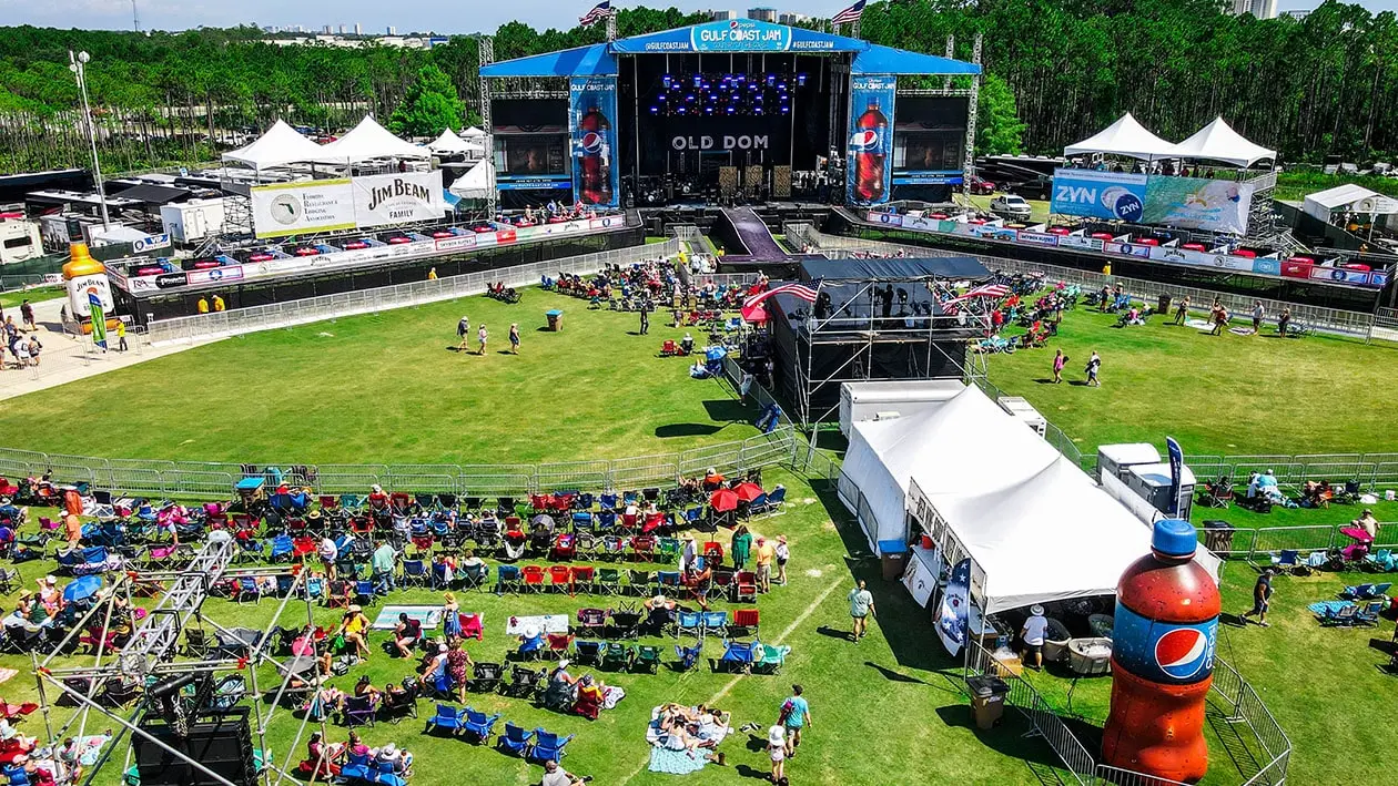 Ariel view of large green lawn with people looking at a large stage